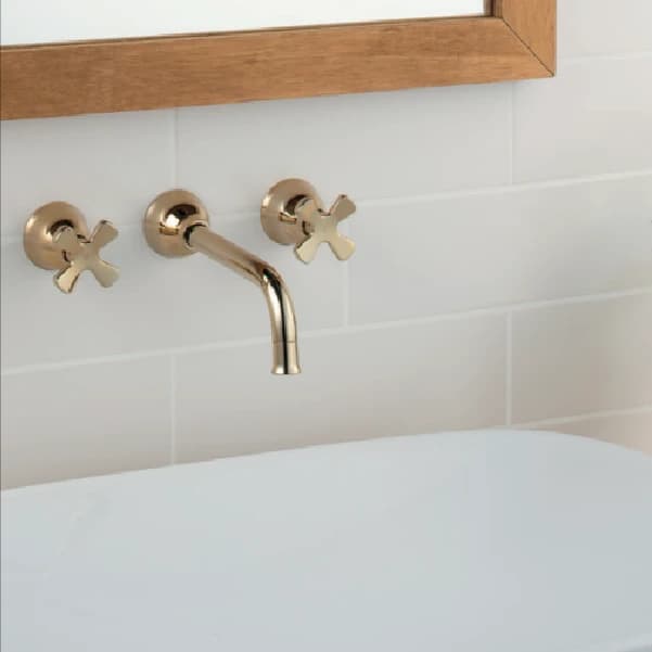 Vòi lavabo gắn tường hai tay vặn chữ thập màu vàng trong phòng tắm